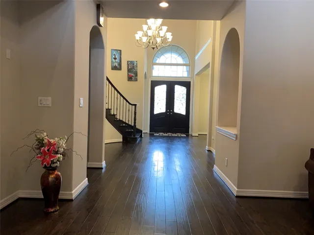 a hallway with wooden floor chandelier and entryway