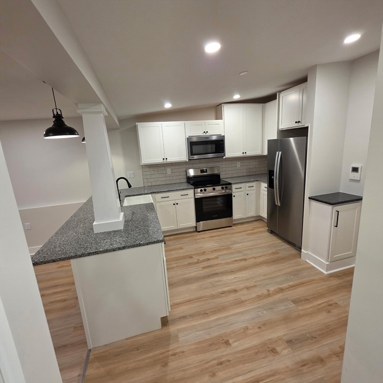 843 Main Street, Unit 107 Clinton, MA 01510 - Photo 4 of 12 a large kitchen with stainless steel appliances granite countertop a stove and a refrigerator