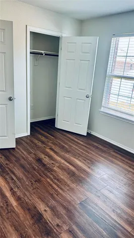 an empty room with wooden floor cabinet and windows