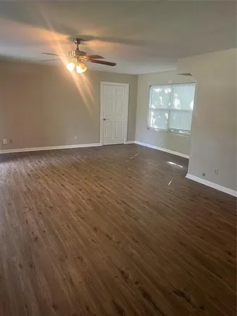 an empty room with wooden floor cabinet and windows