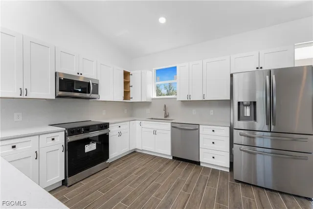 a kitchen with granite countertop white cabinets and stainless steel appliances