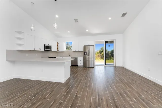 a large kitchen with stainless steel appliances refrigerator wooden floor and a large window