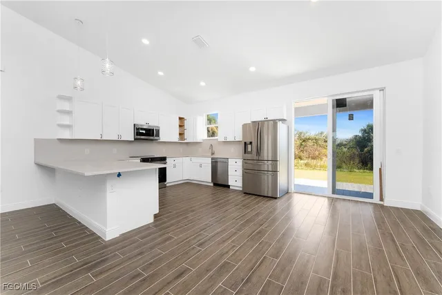a kitchen with stainless steel appliances a refrigerator and wooden floor