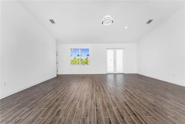 an empty room with wooden floor and window