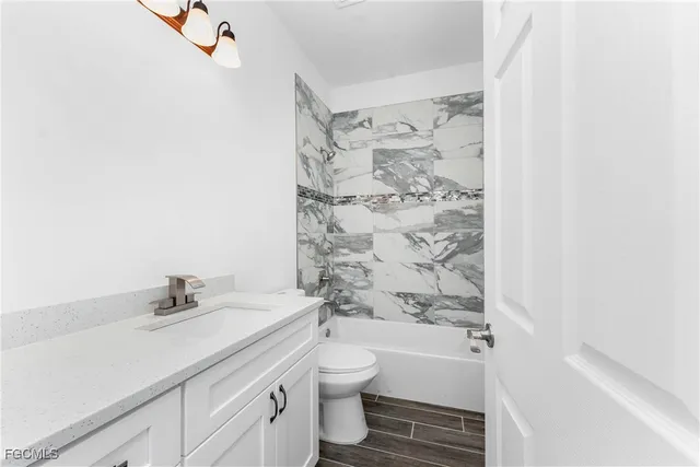 a bathroom with a granite countertop sink a toilet and shower