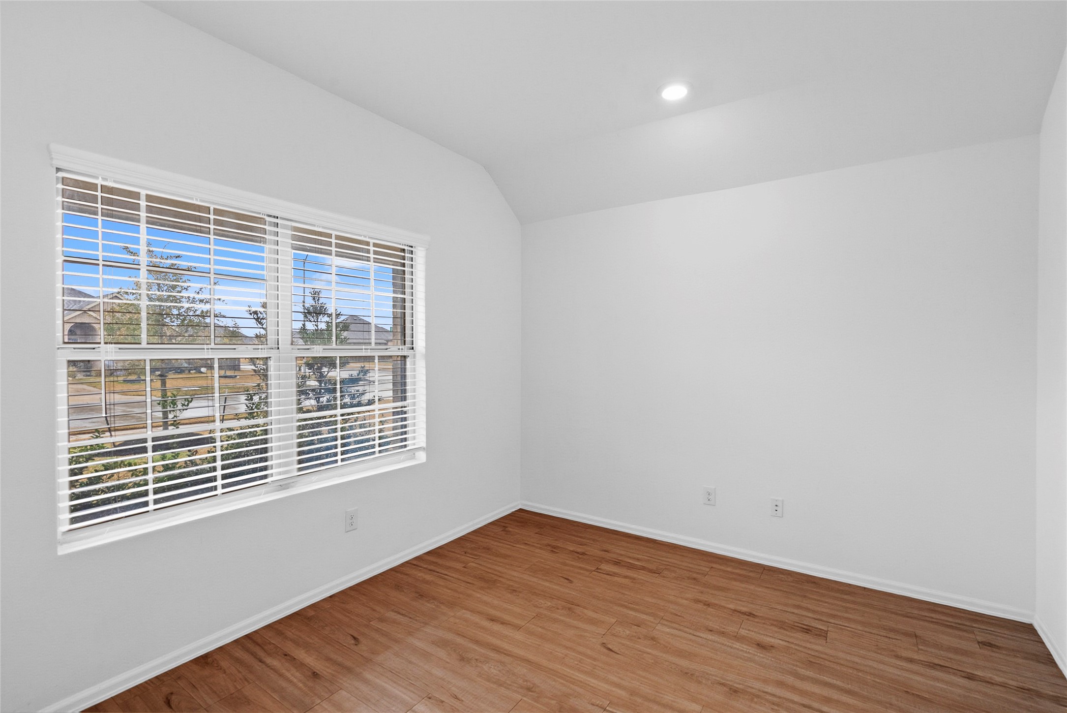 3705 Paloma Fls Lane Rosenberg, TX 77469 - Photo 12 of 27 Bright bedroom with a large street-facing window and crisp white blinds for plenty of daylight. Wood-look flooring and a recessed ceiling light keep the space clean and versatile.