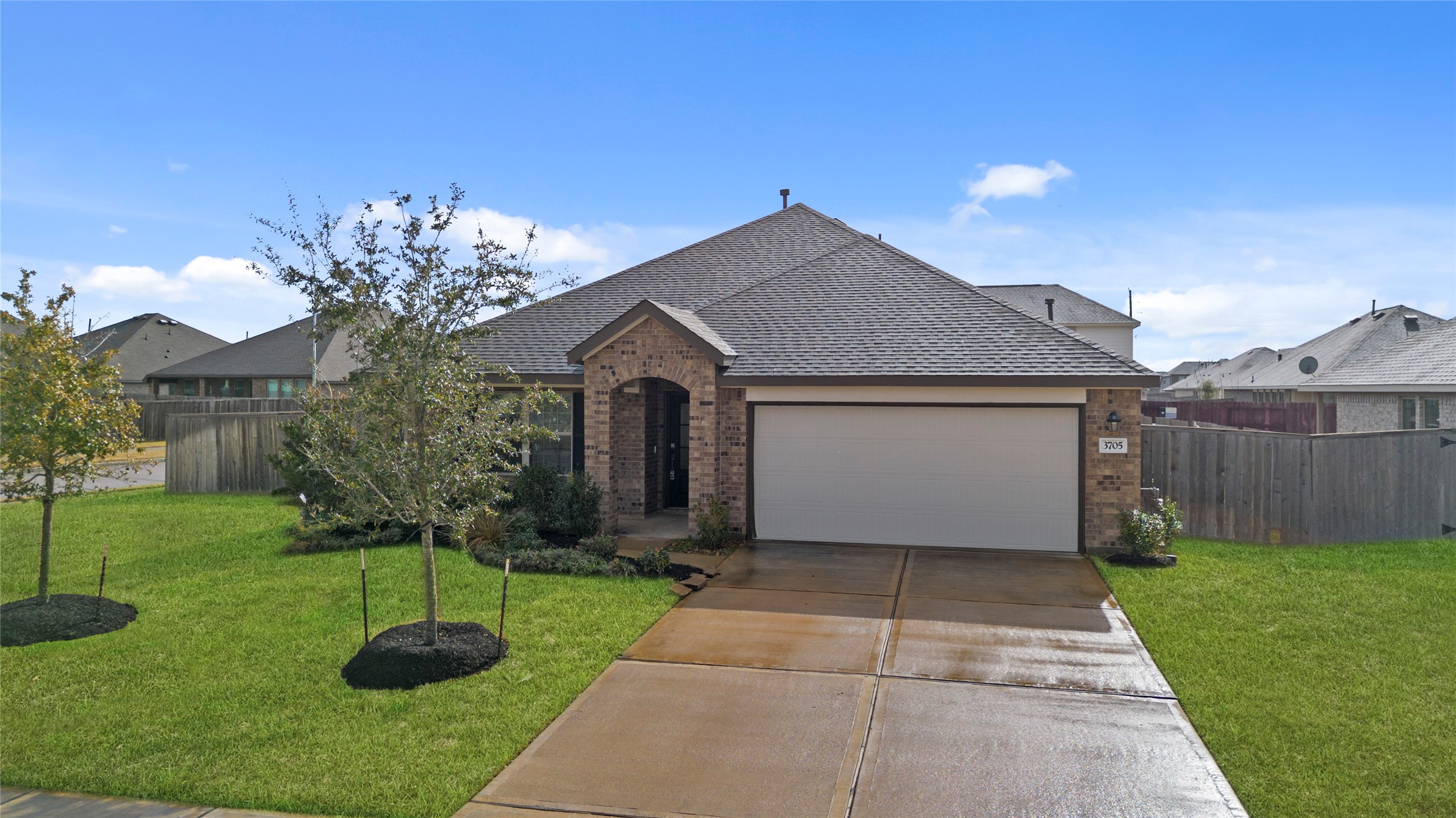 3705 Paloma Fls Lane Rosenberg, TX 77469 - Photo 2 of 27 Classic brick exterior with a two-car garage and a recessed covered entry. Manicured lawn, mulched beds, and young shade trees complete the clean curb appeal under a bright blue sky.