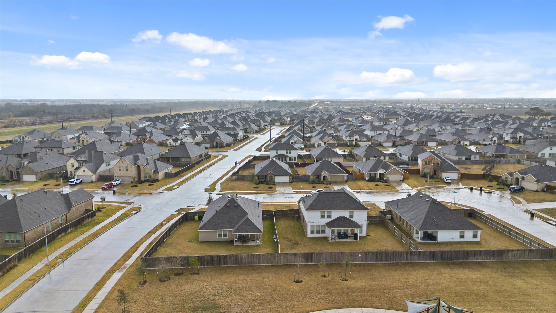 3705 Paloma Fls Lane Rosenberg, TX 77469 - Photo 26 of 27 Elevated aerial view shows the surrounding neighborhood layout with wide streets, sidewalks, and rows of homes extending to the horizon. The view gives a clear sense of the home’s setting within the community.