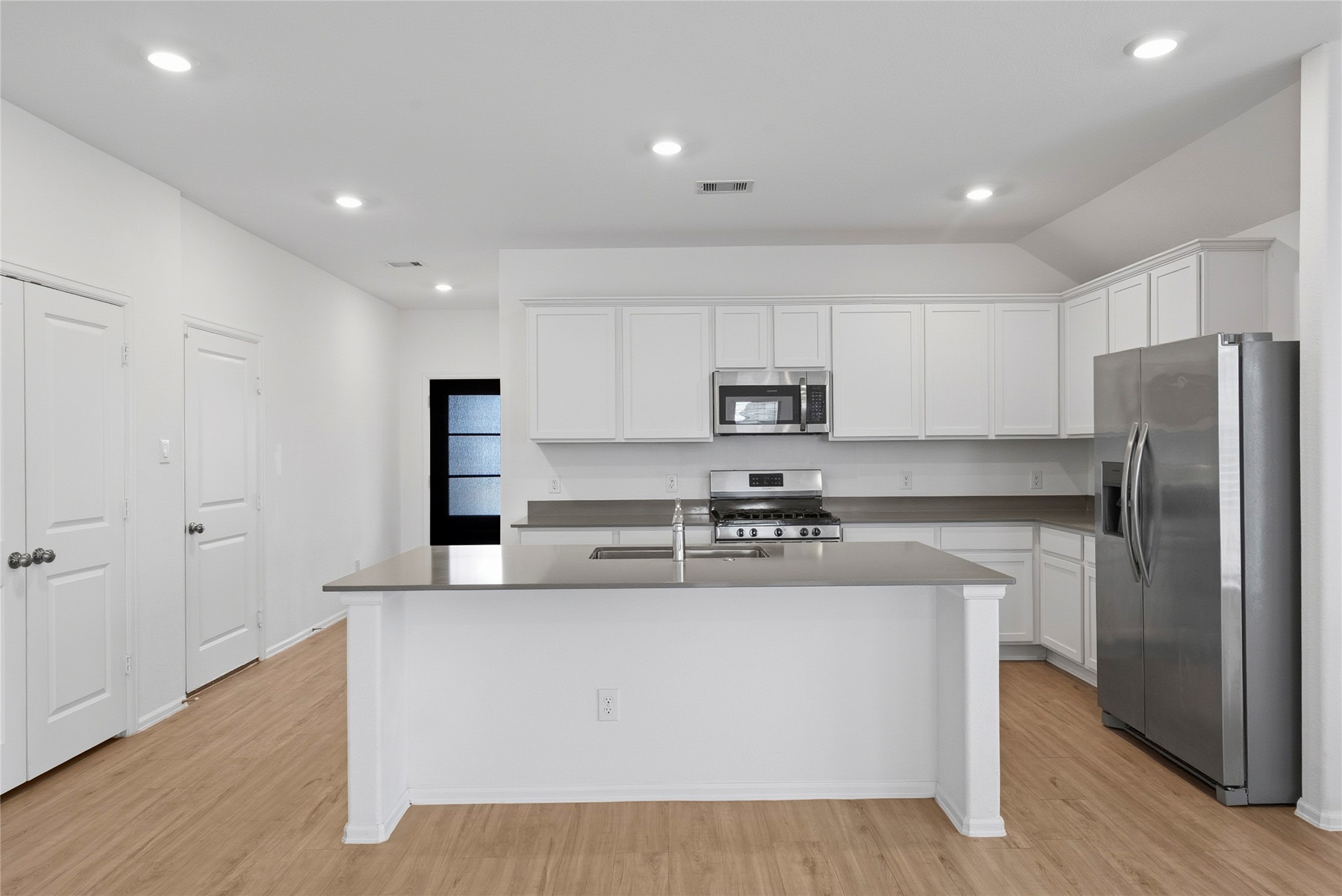 3705 Paloma Fls Lane Rosenberg, TX 77469 - Photo 4 of 27 Open kitchen with a large island and sink, wrapped in white cabinetry and sleek counters. Stainless steel appliances and recessed lighting keep the space bright and modern.
