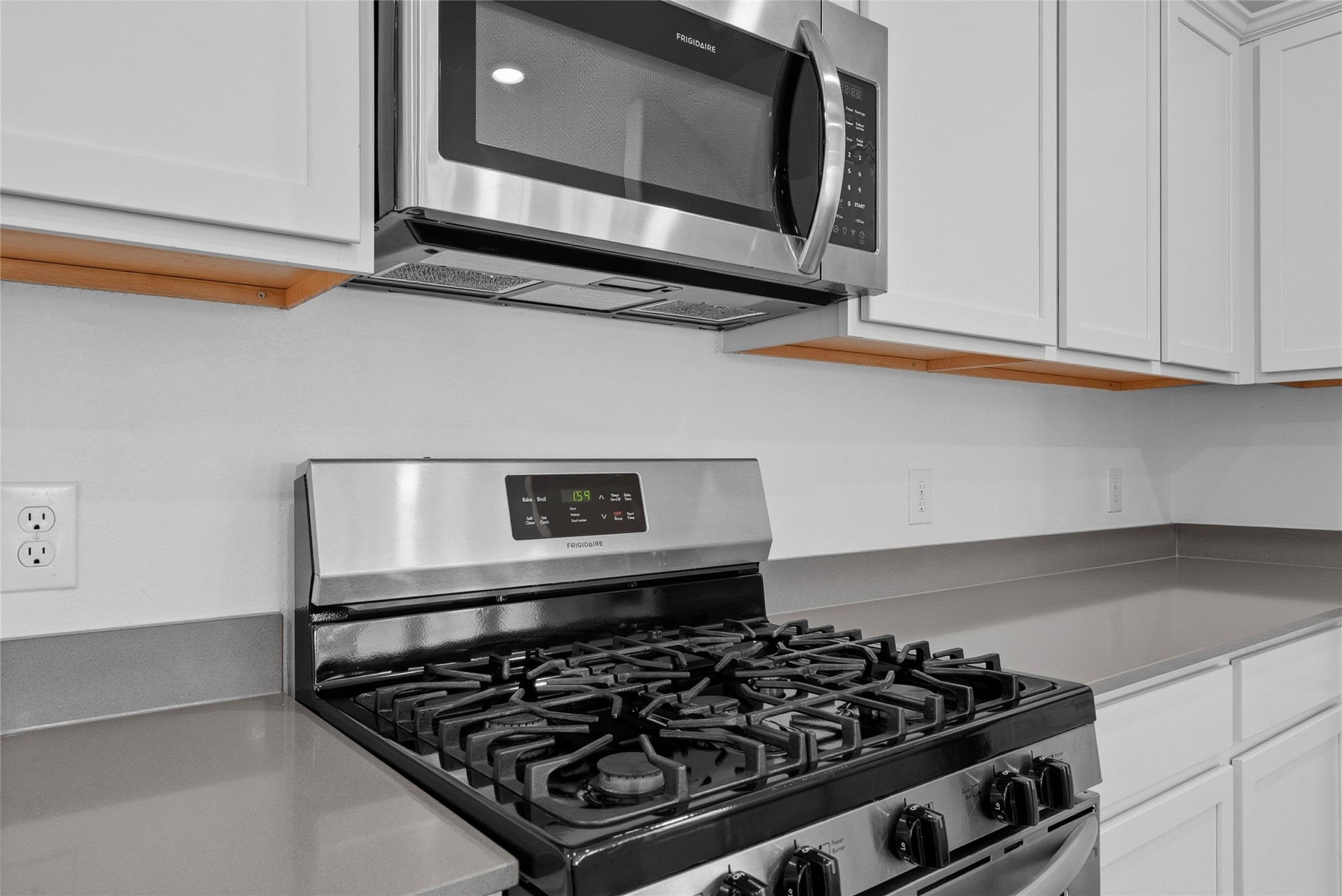 3705 Paloma Fls Lane Rosenberg, TX 77469 - Photo 8 of 27 Stainless gas range sits beneath an over-the-range microwave, framed by clean white cabinetry. Smooth counters provide generous workspace along both sides of the cook area.