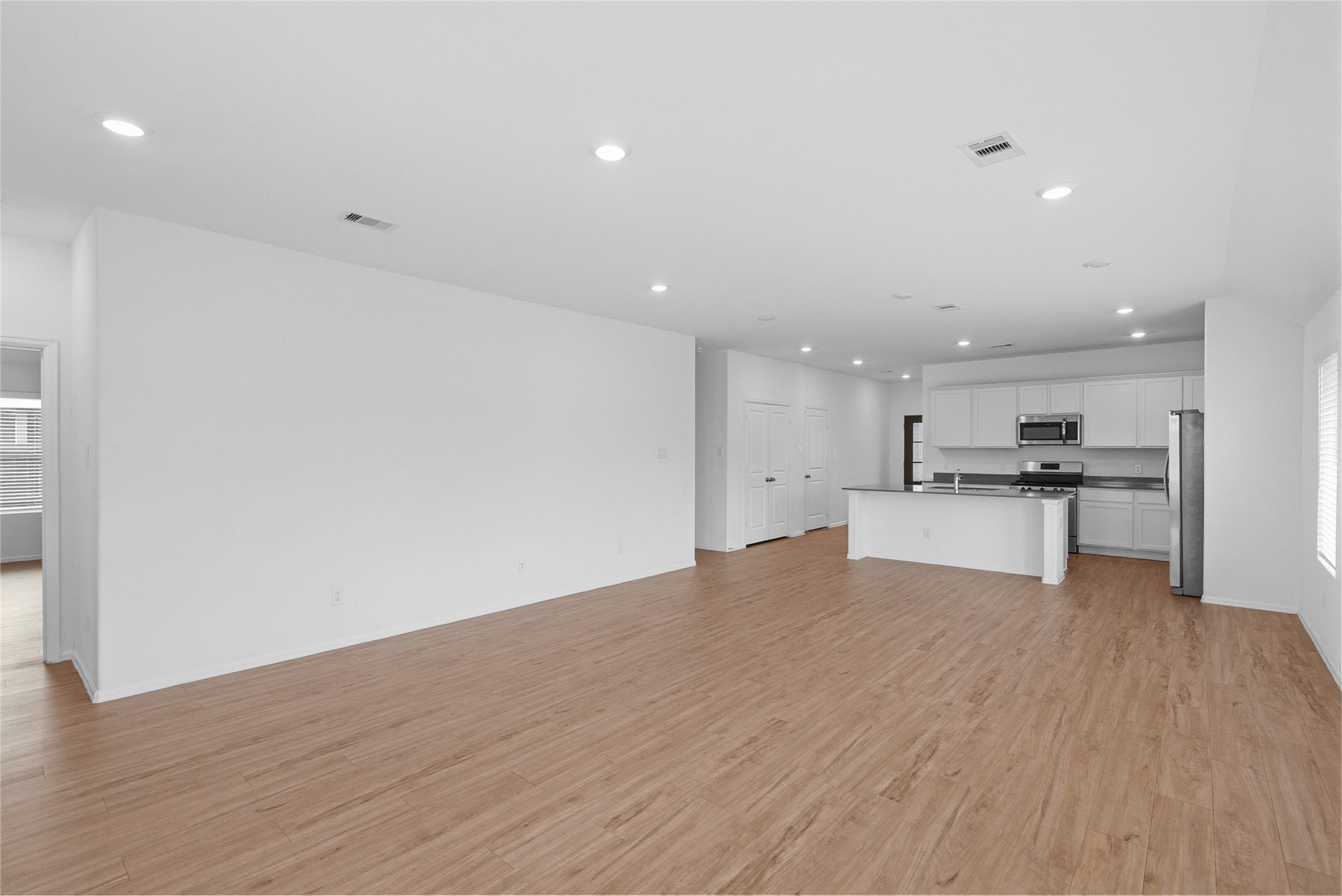 3705 Paloma Fls Lane Rosenberg, TX 77469 - Photo 9 of 27 Wide-open living and dining area flows directly into the kitchen for an easy, connected layout. Wood-look flooring and recessed lighting run throughout, with the island creating a natural gathering point.