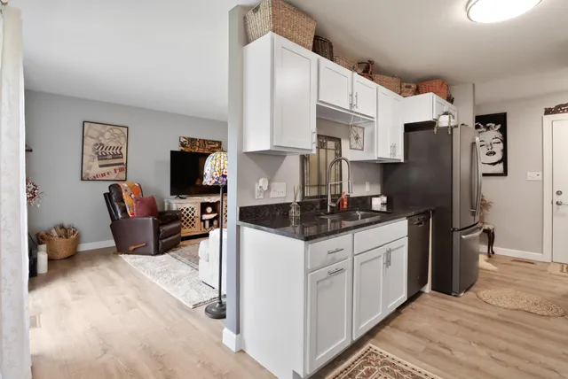 a kitchen with stainless steel appliances granite countertop a refrigerator oven a sink dishwasher and white cabinets with wooden floor