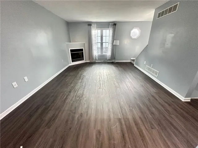 an empty room with wooden floor and fireplace