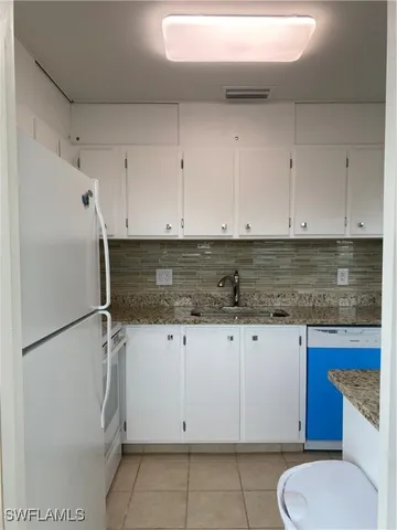 a kitchen with granite countertop white cabinets white stainless steel appliances and a sink