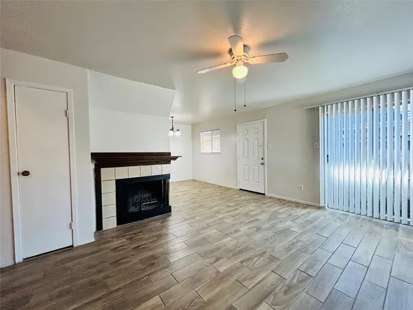 a view of an empty room with wooden floor fireplace and a window