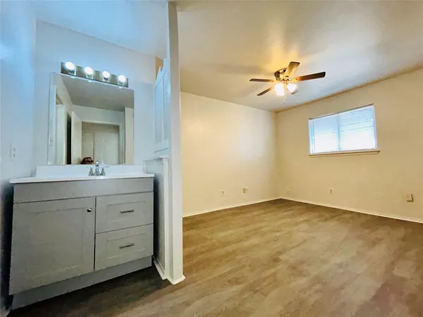 an empty room with wooden floor and ceiling fan