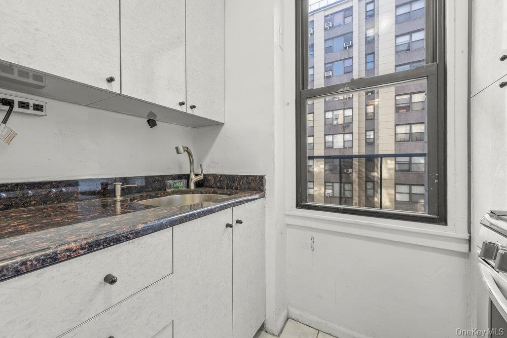 98-26 64th Avenue, Unit 3D Queens, NY 11374 - Photo 8 of 11 a kitchen with granite countertop a sink and a window