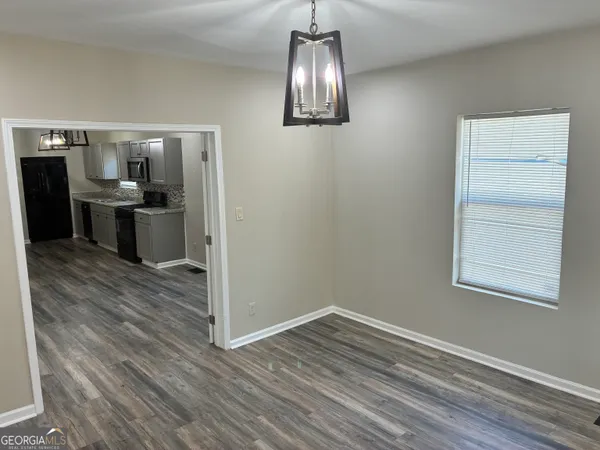 a view of a big room with wooden floor kitchen and windows