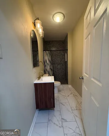 a bathroom with a sink a toilet a mirror and shower