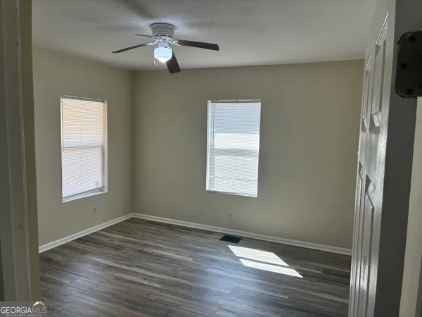 an empty room with wooden floor cabinet and windows