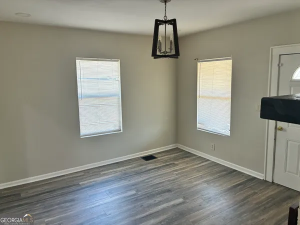 a view of an empty room with a window and wooden floor