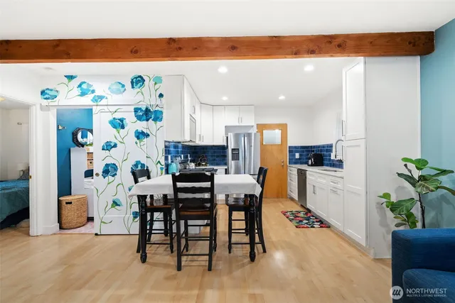 a kitchen with stainless steel appliances a dining table chairs and refrigerator