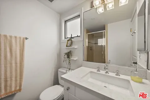 a bathroom with a granite countertop sink toilet and mirror