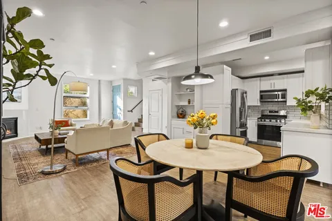 a kitchen with stainless steel appliances a dining table chairs and stove