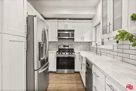 a kitchen with stainless steel appliances granite countertop a refrigerator a stove and a sink