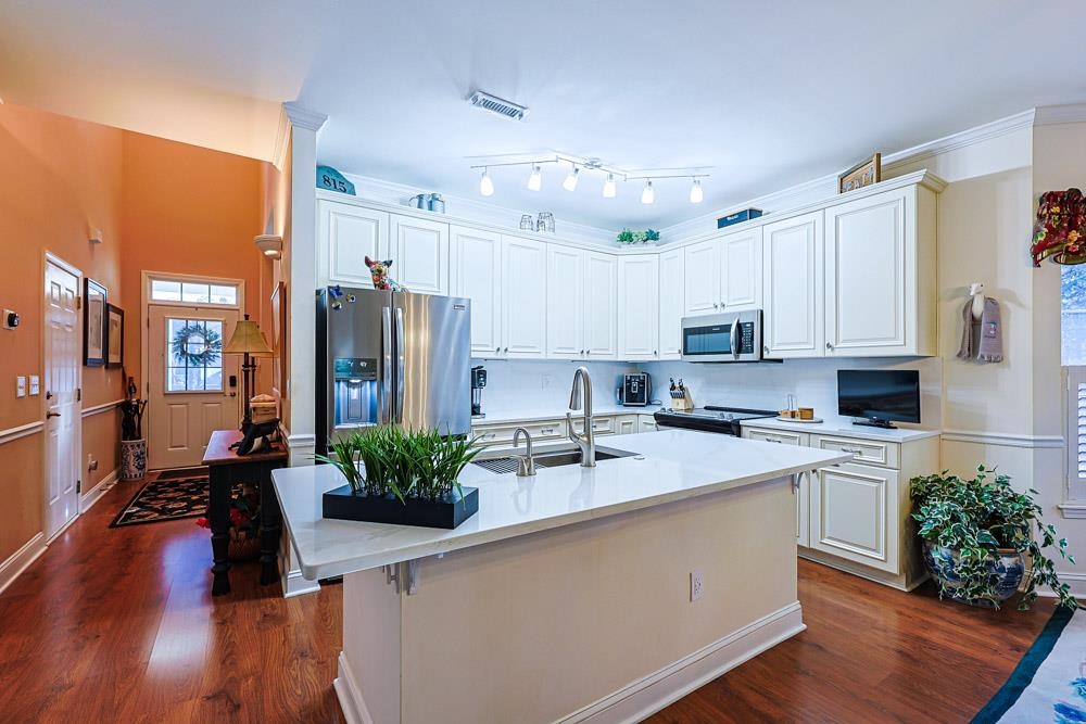815 Botany Loop, Unit 815 Murrells Inlet, SC 29576 - Photo 7 of 40 Kitchen featuring appliances with stainless steel finishes, white cabinets, a kitchen island with sink, dark wood-type flooring, and crown molding