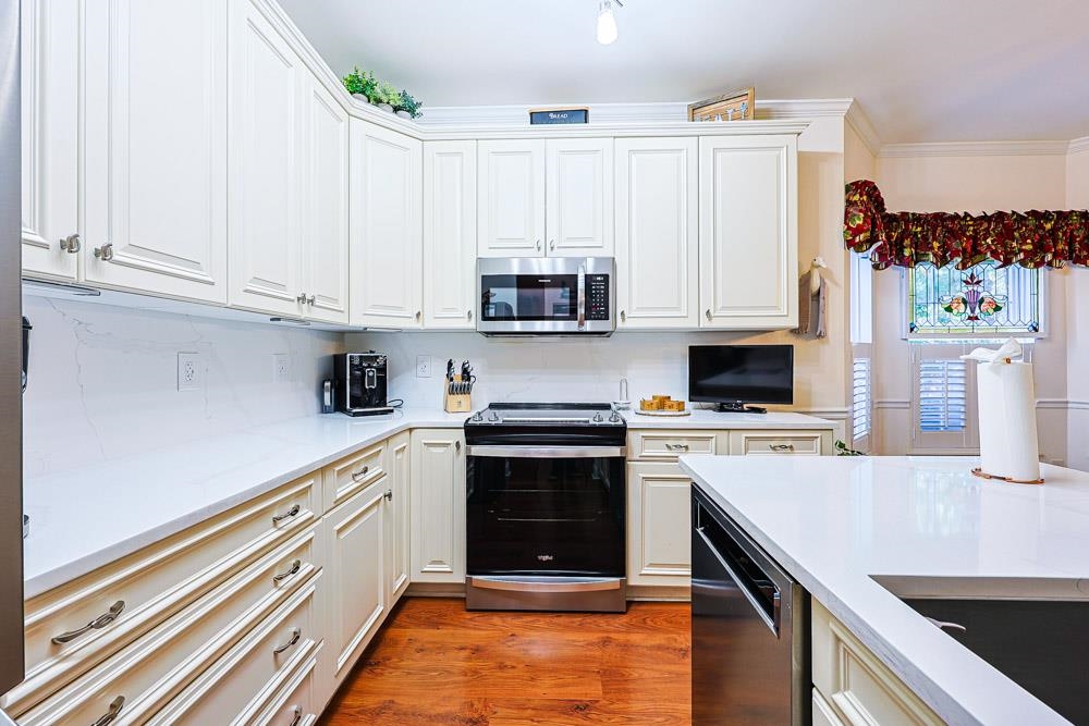 815 Botany Loop, Unit 815 Murrells Inlet, SC 29576 - Photo 10 of 40 Kitchen with stainless steel appliances, white cabinets, light stone counters, light wood finished floors, and crown molding