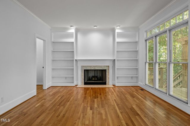 a view of a room with wooden floor a fireplace and windows