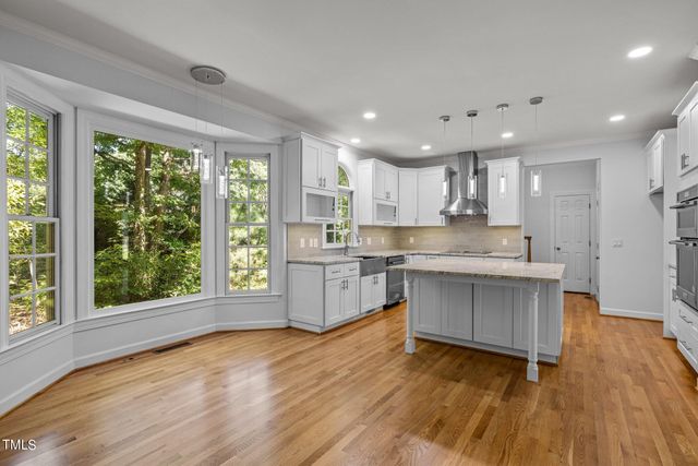 a kitchen with a wooden floor sink stainless steel appliances and window