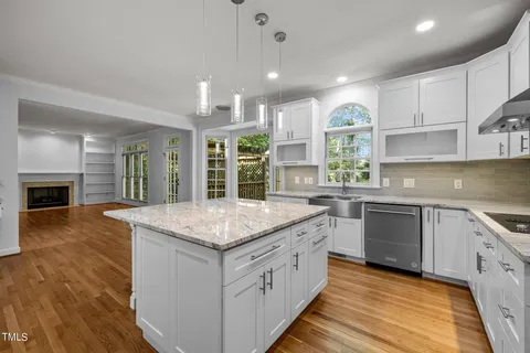 a kitchen with stainless steel appliances granite countertop hardwood floor sink stove and wooden cabinets