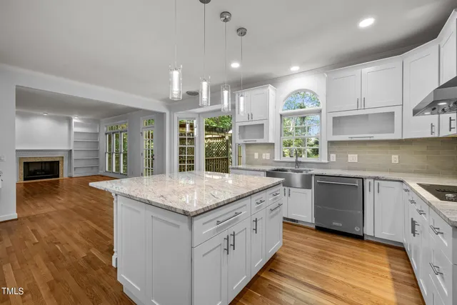 a kitchen with stainless steel appliances granite countertop hardwood floor sink stove and wooden cabinets