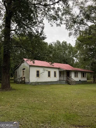 a view of a house with a big yard and large trees
