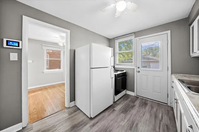 a kitchen with a refrigerator a stove top oven a sink and dishwasher with wooden floor