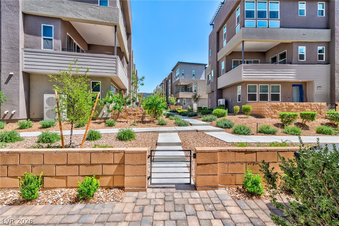 3327 Esker Rdg Avenue Henderson, NV 89044 - Photo 23 of 24 A meticulously maintained communal landscape with a charming gate welcomes residents to modern multi-story dwellings.