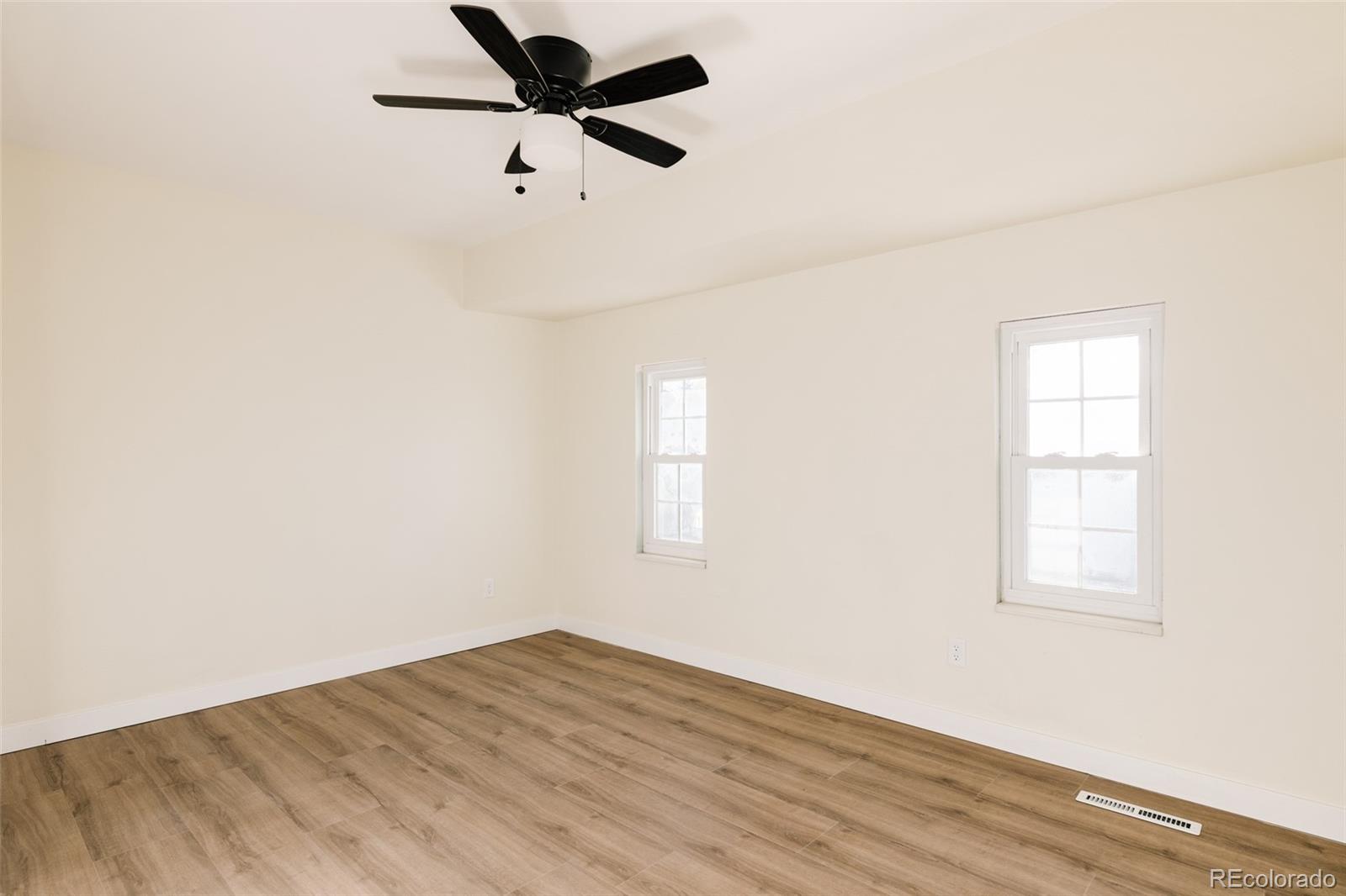 7580 South Lost Ranger Peak Littleton, CO 80127 - Photo 22 of 34 an empty room with wooden floor ceiling fan and windows