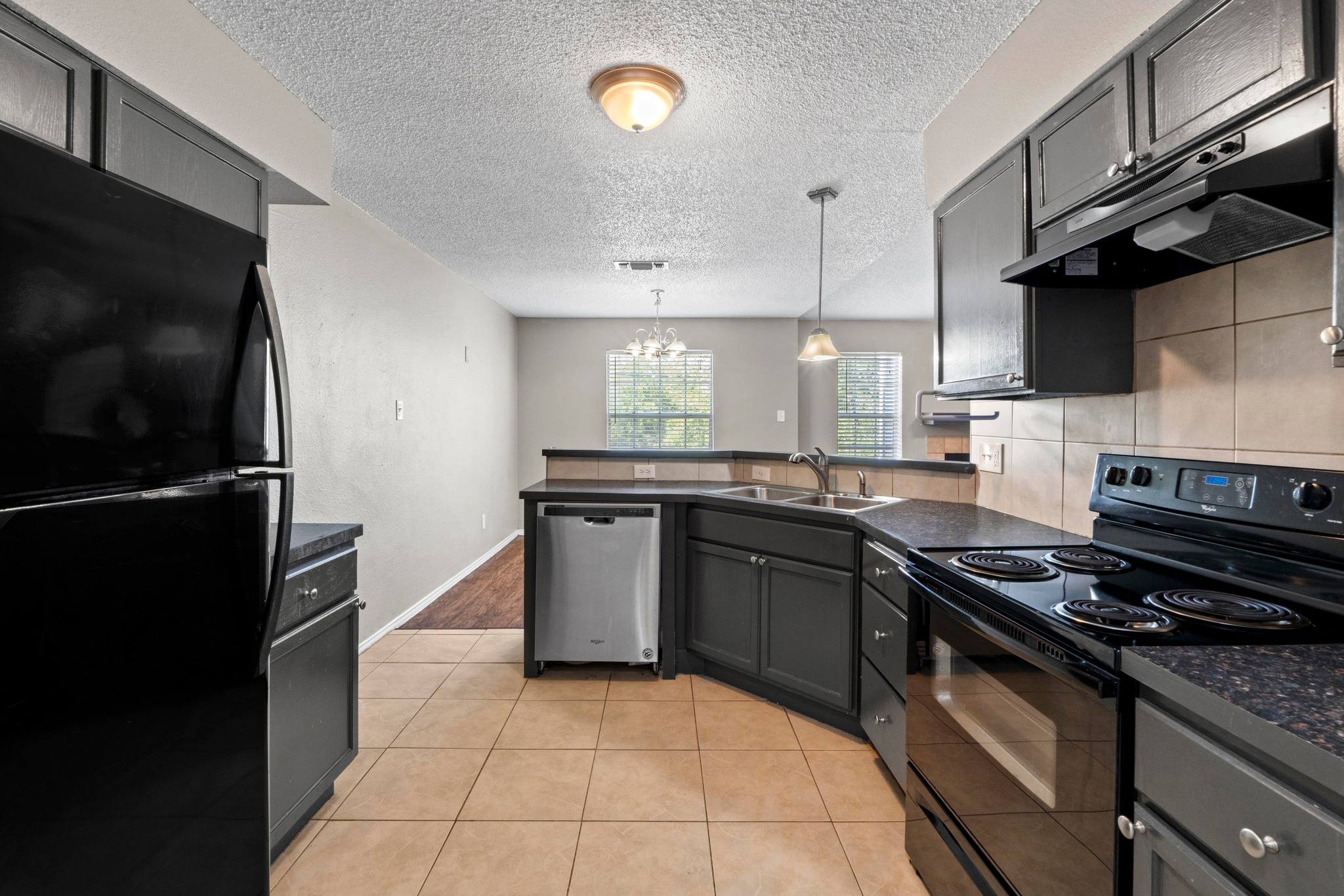 4208 Duval Road, Unit C Austin, TX 78759 - Photo 11 of 28 Kitchen with black appliances, a peninsula, range hood, dark countertops, and a textured ceiling