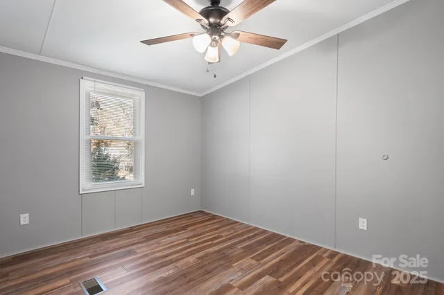 a view of an empty room with window and wooden floor