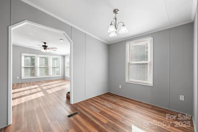 a view of an empty room with wooden floor and windows