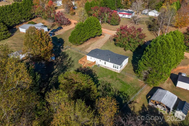 an aerial view of residential house with outdoor space and trees all around