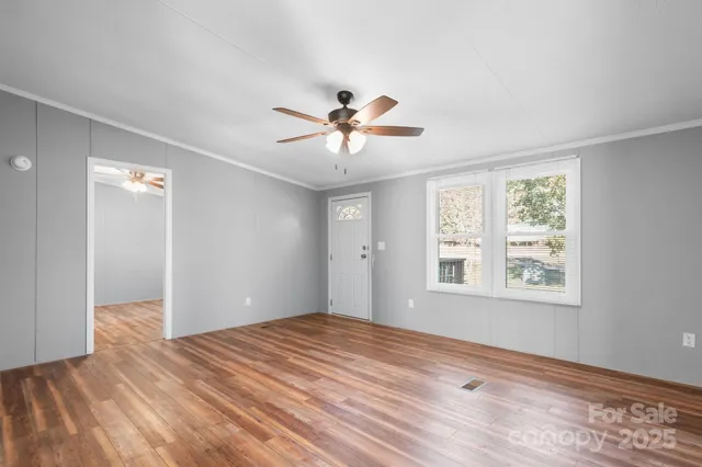 a view of empty room with wooden floor and fan