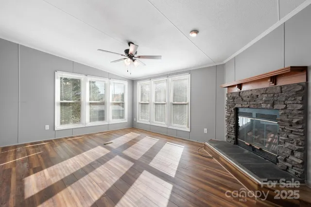 a view of an empty room with wooden floor and a fireplace
