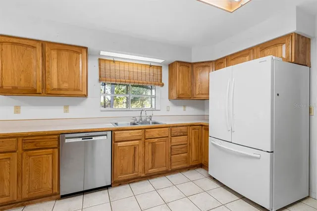a white kitchen with stainless steel appliances granite countertop a refrigerator sink and cabinets