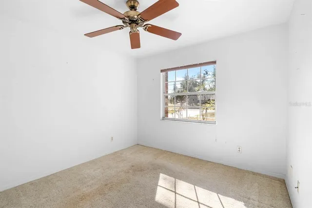 an empty room with a window and a fan