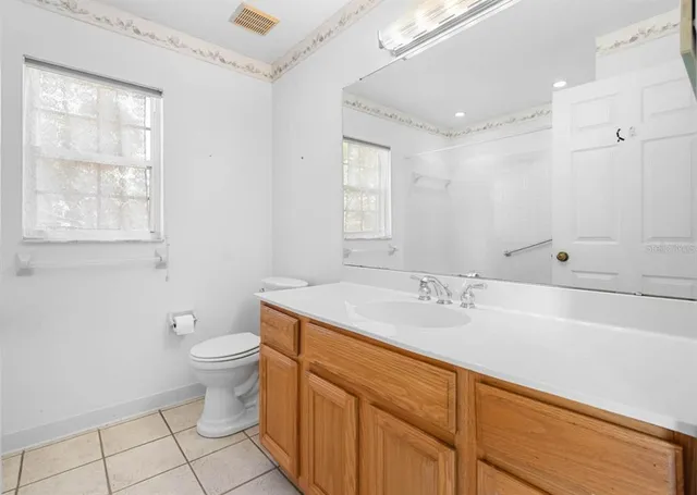 a bathroom with a granite countertop sink a toilet a mirror and a bathtub