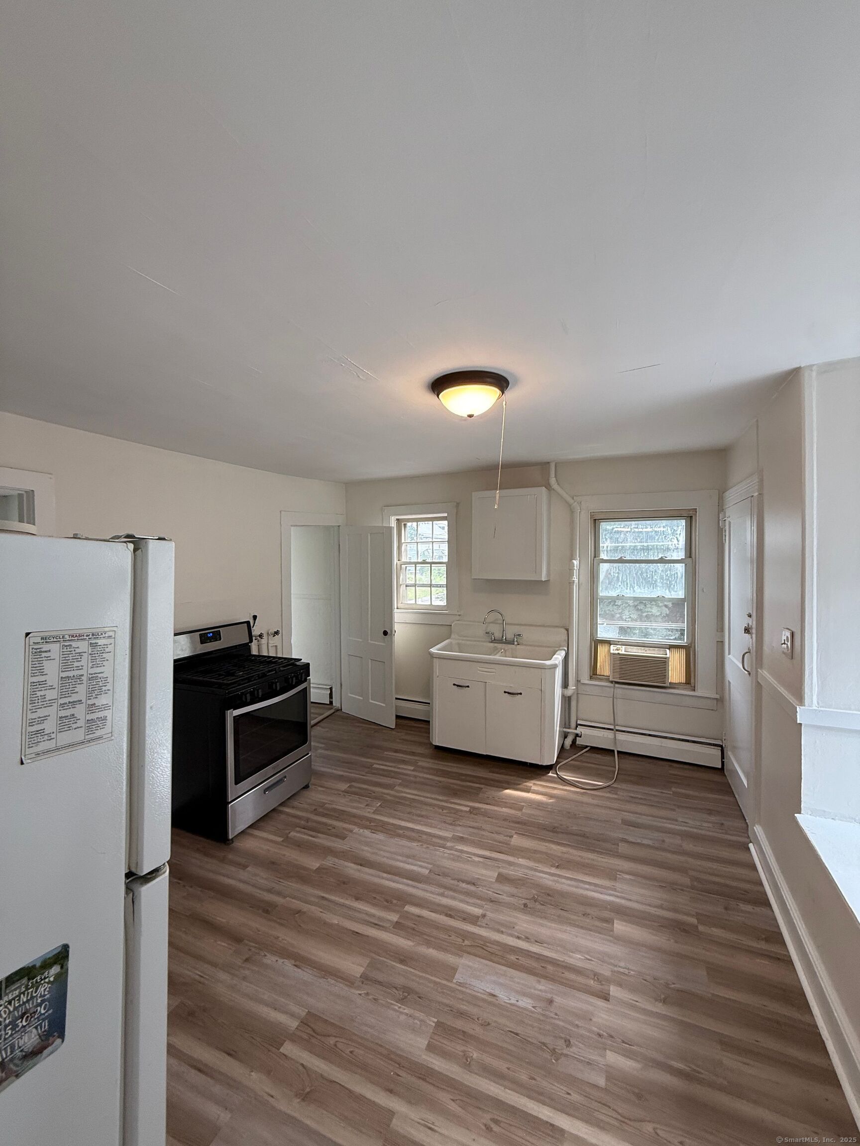 a view of a kitchen with wooden floor electronic appliances and windows