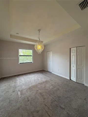 an empty room with windows and chandelier fan